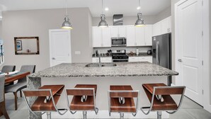 A modern kitchen with granite countertops, stainless steel appliances, and pendant lighting.