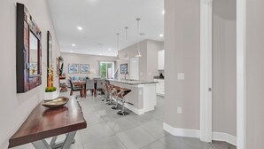 A modern kitchen with a central island, bar stools, and pendant lighting.