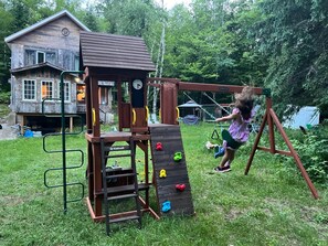 Eine Spielanlage aus Holz mit Kletterwand und Schaukeln.