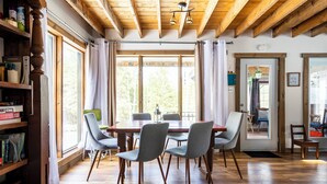 Un espace repas comprenant une table en bois, quatre chaises grises et un plancher en bois.