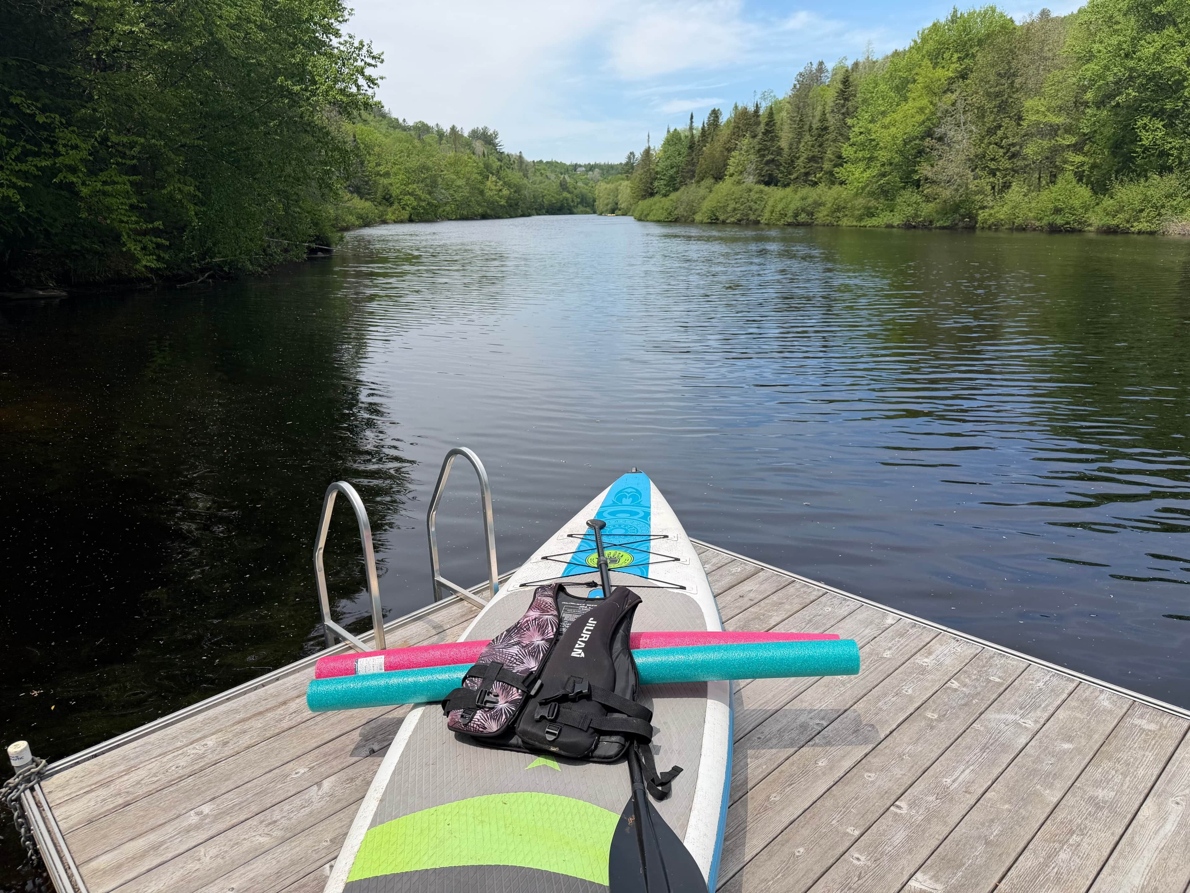 Une jetée en bois avec une planche de paddle et de l’équipement.