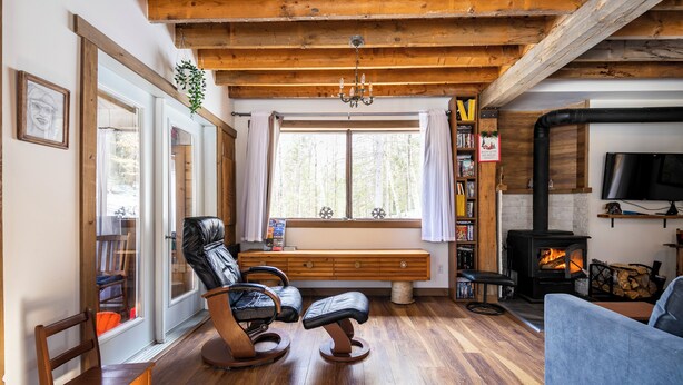 Un salon chaleureux avec un plancher en bois, une cheminée, un canapé, un banc et un téléviseur.
