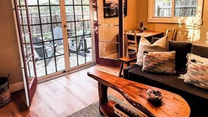 A cozy living room with a wooden coffee table, a sofa with cushions, and a dining area with a table and chairs. - The Nest: Serene Sanctuary w Hot Tub, Fireplace, Grill, Hammock, Outdoor Fire Fe (Idyllwild-Pine Cove)
