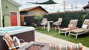 A backyard with a hot tub, lounge chairs, a table, and a fire pit. - Charming Boutique Hotel with Private Hot Tub
 (De Beque)