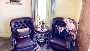 A living room with two leather armchairs, a small side table with a lamp, and a television mounted on the wall. - Charming Boutique Hotel with Private Hot Tub
 (De Beque)
