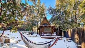 Une cabane en bois dotée d’une véranda qui fait le tour de la maison, entourée d’un paysage enneigé et d’arbres.