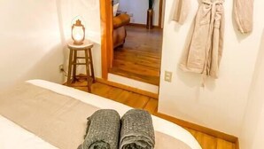 Une chambre à coucher avec un lit, une robe suspendue et un petit tabouret sur lequel est posée une lampe.