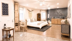 A spacious bedroom with a large bed, a wooden desk, a dining area, and a kitchen. - Creekside Sanctuary | Fire Pit | Hot Tub (Idyllwild-Pine Cove)