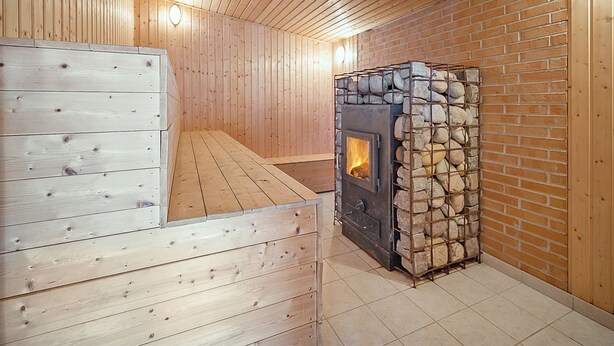 A sauna room with wooden walls and a stone fireplace.