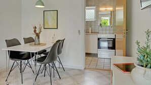 A modern kitchen with white cabinets, a stainless steel oven, and a window with blinds.