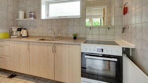 A modern kitchen with a built-in oven, a sink, and a window above the countertop.