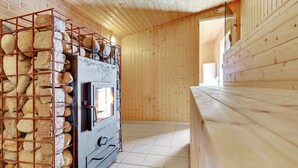 A rustic wooden cabin interior with a stone wall oven, wooden flooring, and a wooden bench.