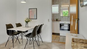 A modern kitchen with white cabinets, a stainless steel oven, and a window with a view of greenery.