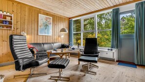 A cozy living room with a wooden ceiling, a black leather sofa, a black leather armchair, and a wooden coffee table. - "Hira" - 300m from the sea by Interhome (Væggerløse)