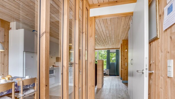 A narrow hallway with wooden walls and a tiled floor leading to a kitchen area with white cabinets and a refrigerator. - "Hira" - 300m from the sea by Interhome (Væggerløse)