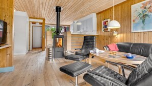 A cozy cabin interior with a wood-burning stove, leather seating, and wooden walls. - "Hira" - 300m from the sea by Interhome (Væggerløse)