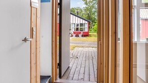 A wooden door leading to an outdoor deck with a red and white building in the background. - "Hira" - 300m from the sea by Interhome (Væggerløse)