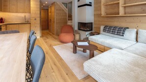 Un intérieur moderne avec une table à manger en bois, des chaises, un canapé, une cheminée et un escalier.
