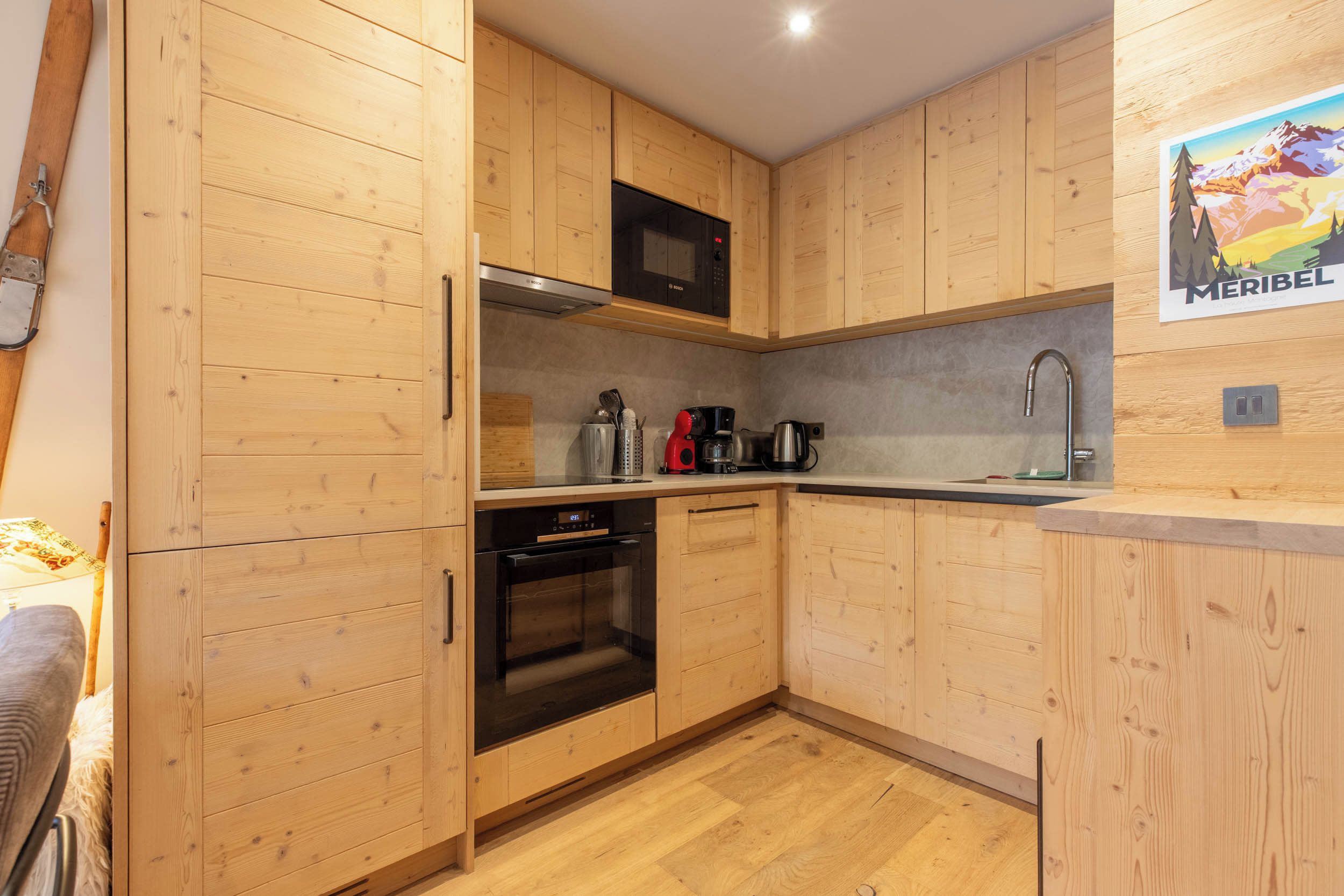 A compact kitchen with wooden cabinets, a Bosch microwave, a coffee maker, and a sink.