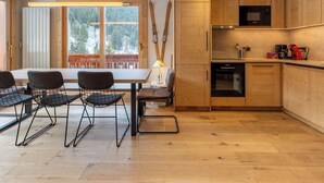 Une cuisine moderne dotée de meubles en bois, d’un four à micro-ondes et d’une machine à café. Un coin repas avec une table et des chaises est également disponible.