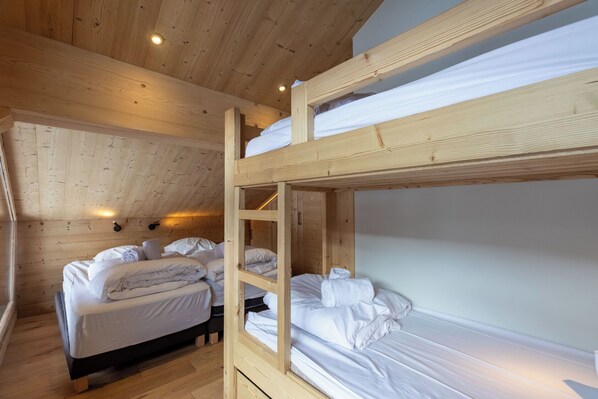 A wooden cabin with bunk beds, a wooden ceiling, and a window.