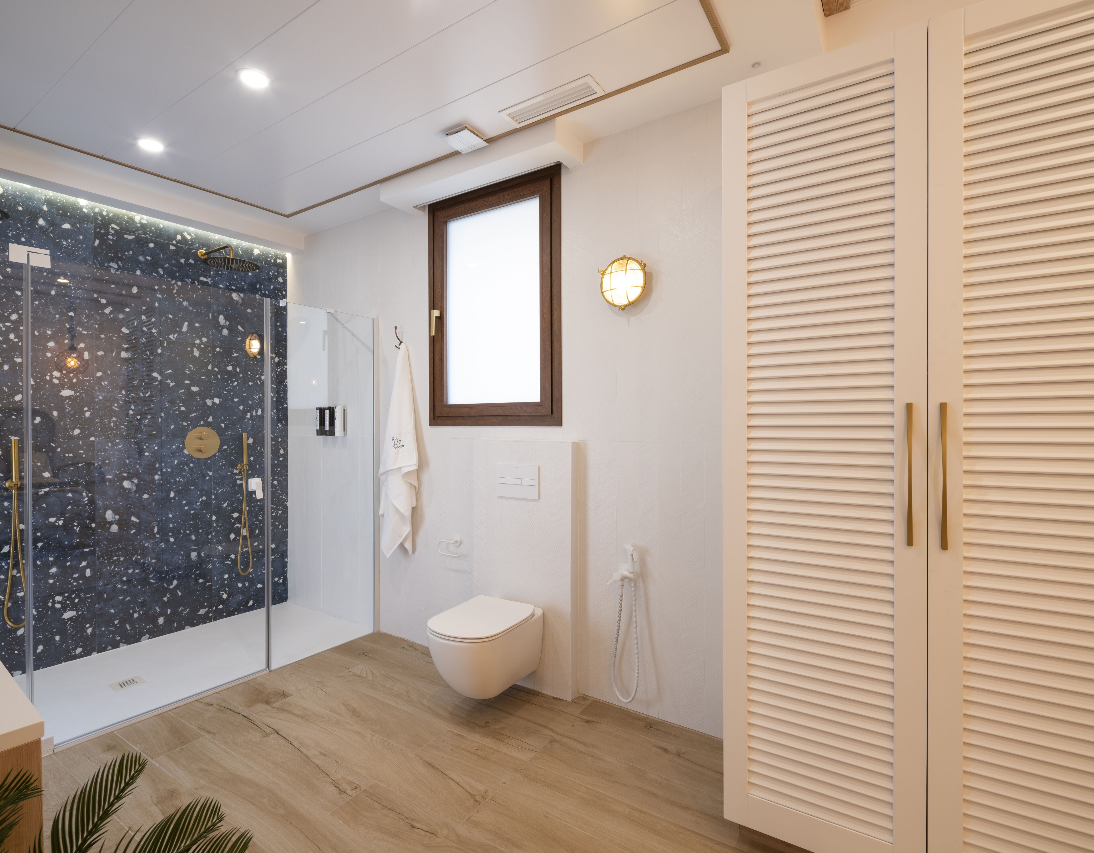 Un baño moderno con ducha de vidrio, inodoro y tocador con espejo.