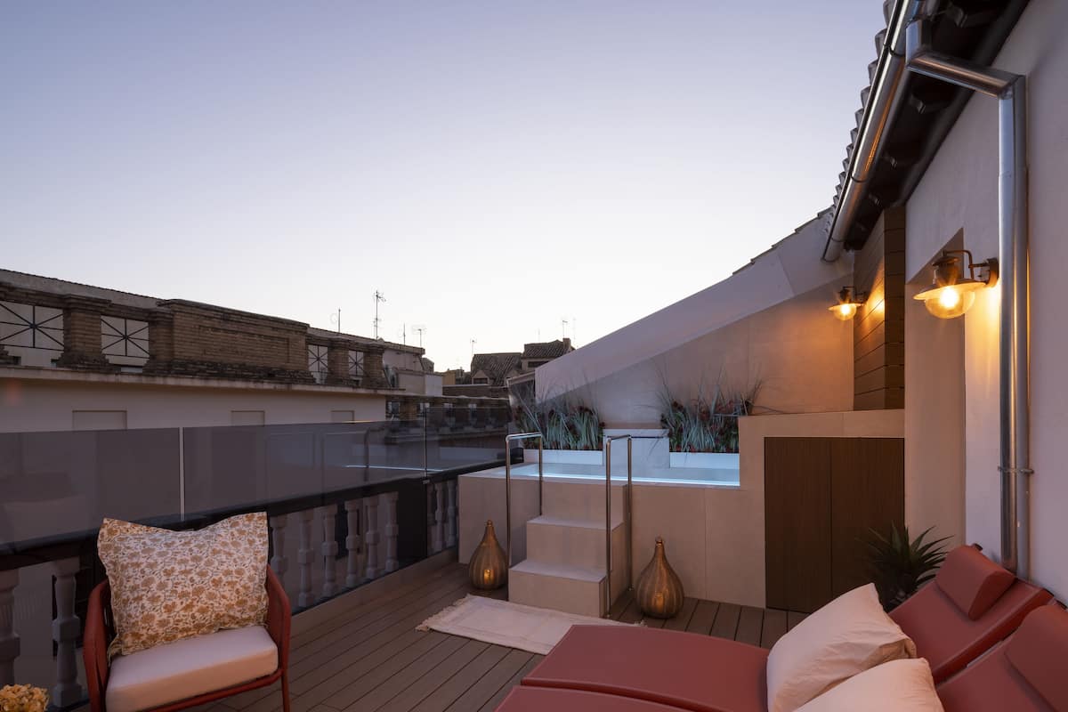 A rooftop terrace with a seating area, a view of the cityscape, and a modern architectural design.