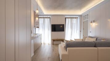 Una sala moderna con un sofá, un televisor montado en la pared y piso de madera.