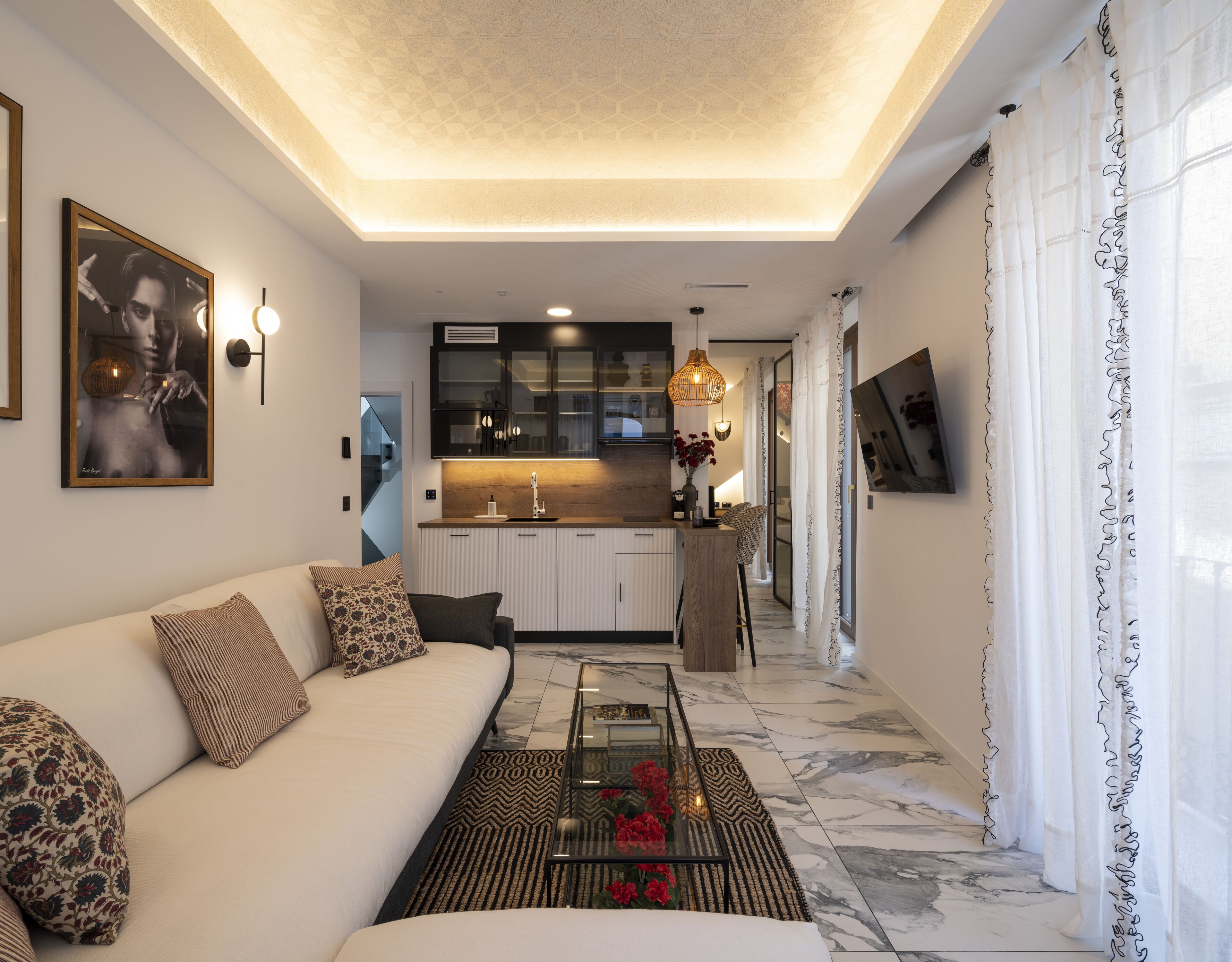 Una sala de estar moderna con un sofá, una mesa de centro y una cocina al fondo.