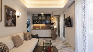 Una sala de estar moderna con un sofá, una mesa de centro y una cocina al fondo.