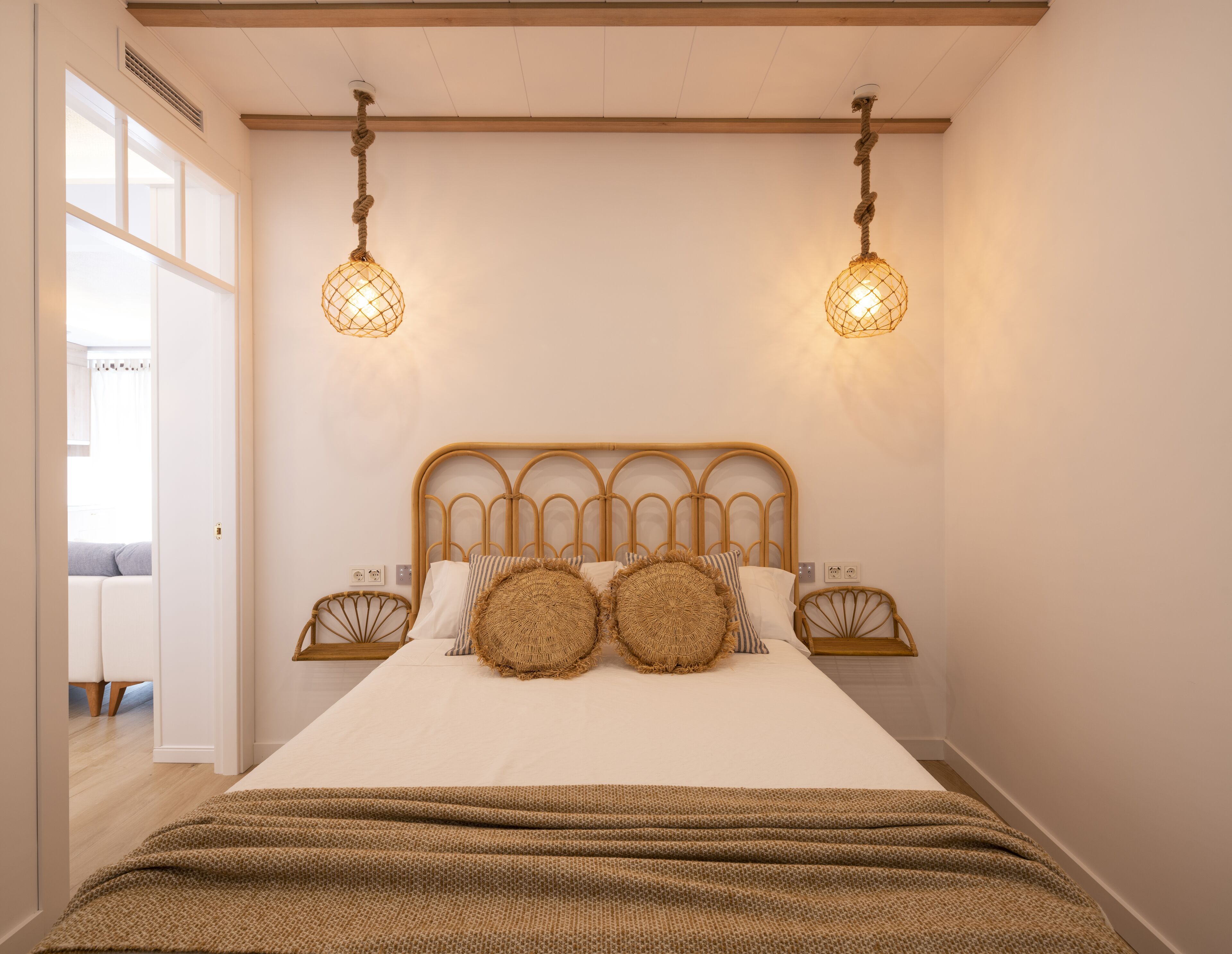 A bedroom with a bed, two wall-mounted lights, and a window.
