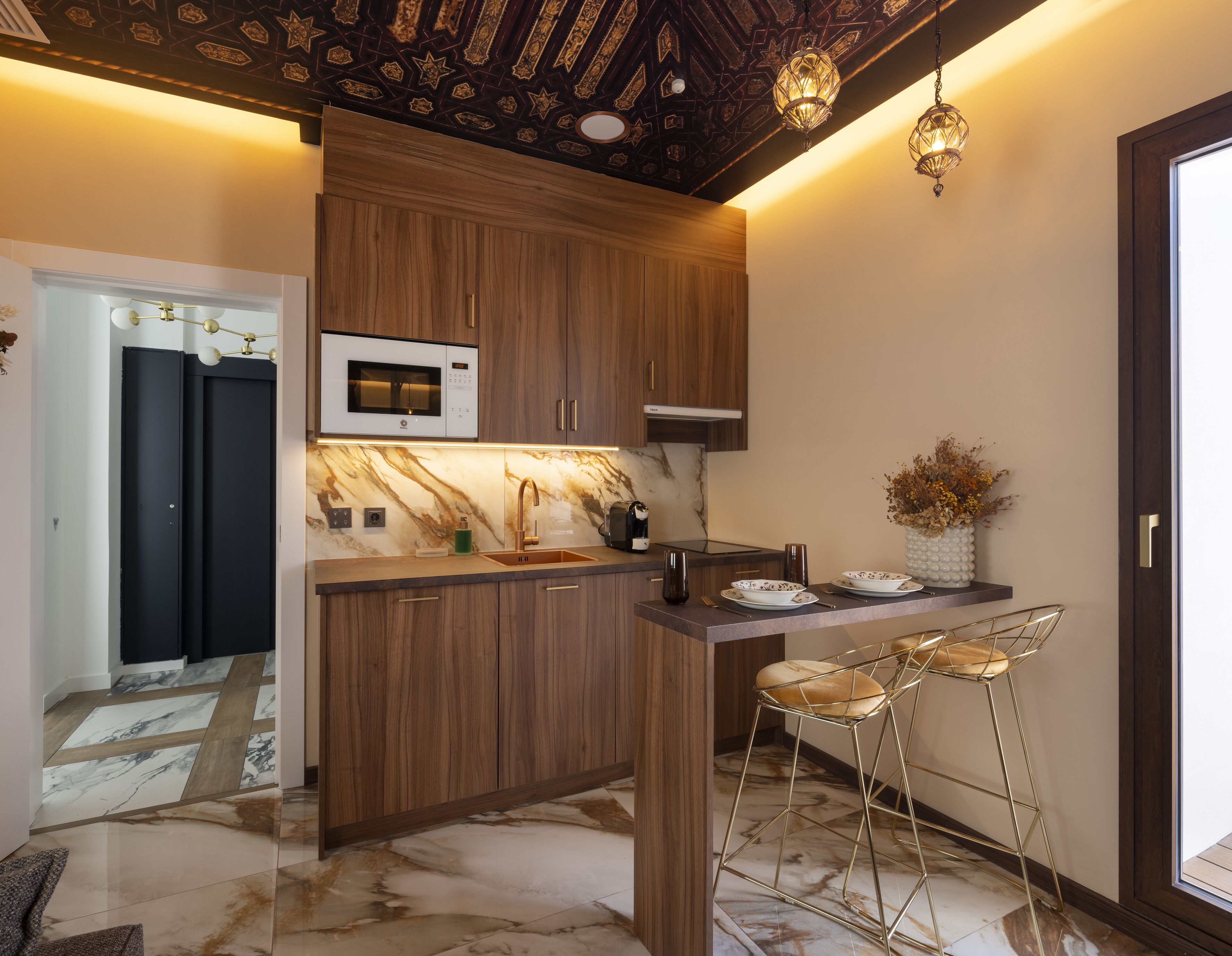 Uma cozinha moderna com armários de madeira, bancada de mármore e um espaço de bar com banquetas.