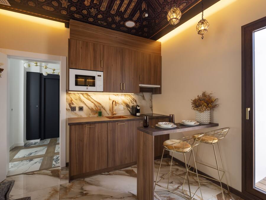Uma cozinha moderna com armários de madeira, bancada de mármore e um espaço de bar com banquetas.