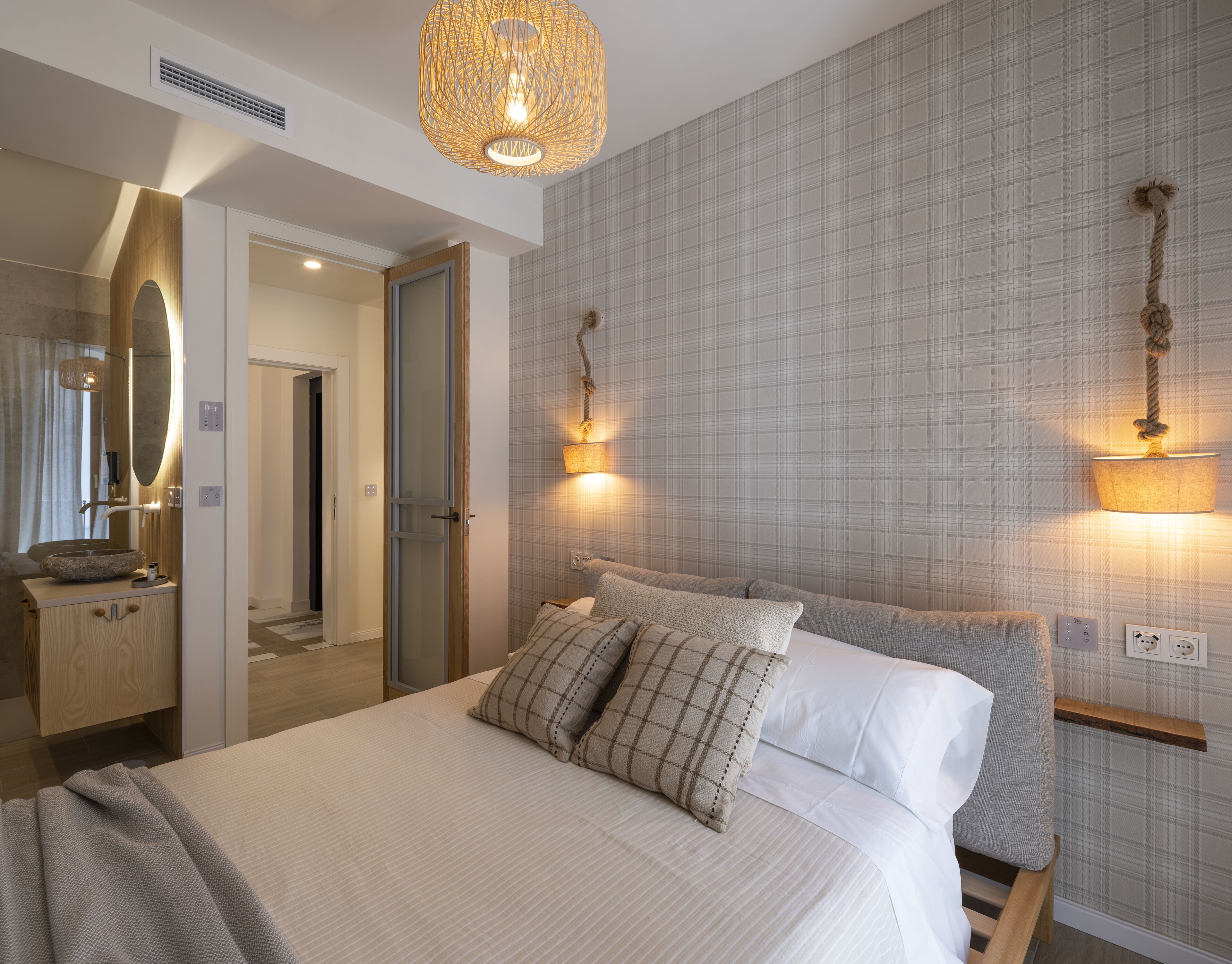 A modern bedroom with a large bed, bedside lamps, a mirror, and a wooden nightstand.