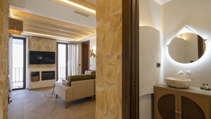 A modern living room with a stone wall, a flat-screen TV, a fireplace, and a sofa. - Palatina Concept Suites (Granada)