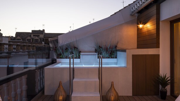A rooftop terrace with a built-in seating area, two large vases, and a view of the cityscape. - Palatina Concept Suites (Granada)