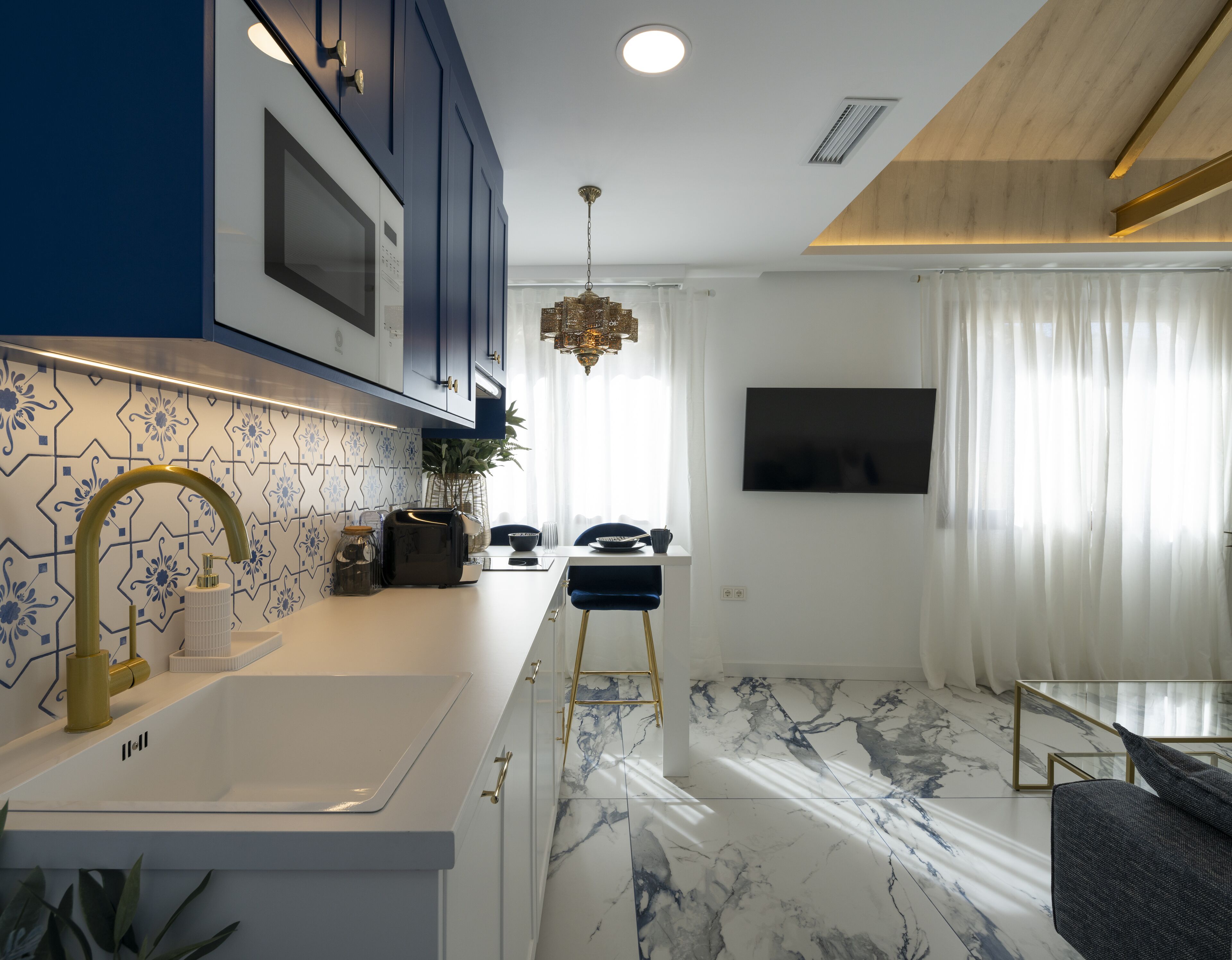 A modern kitchen with a white countertop, blue cabinets, and a marble floor.