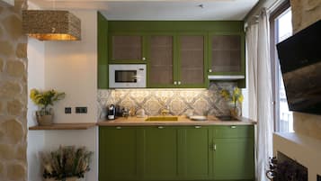 A modern kitchen with green cabinets, a microwave, and a hanging light fixture.