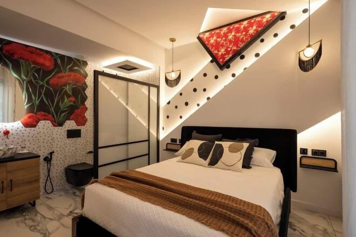 A modern bedroom with a bed, a nightstand, a wall-mounted lamp, and a decorative wall panel.