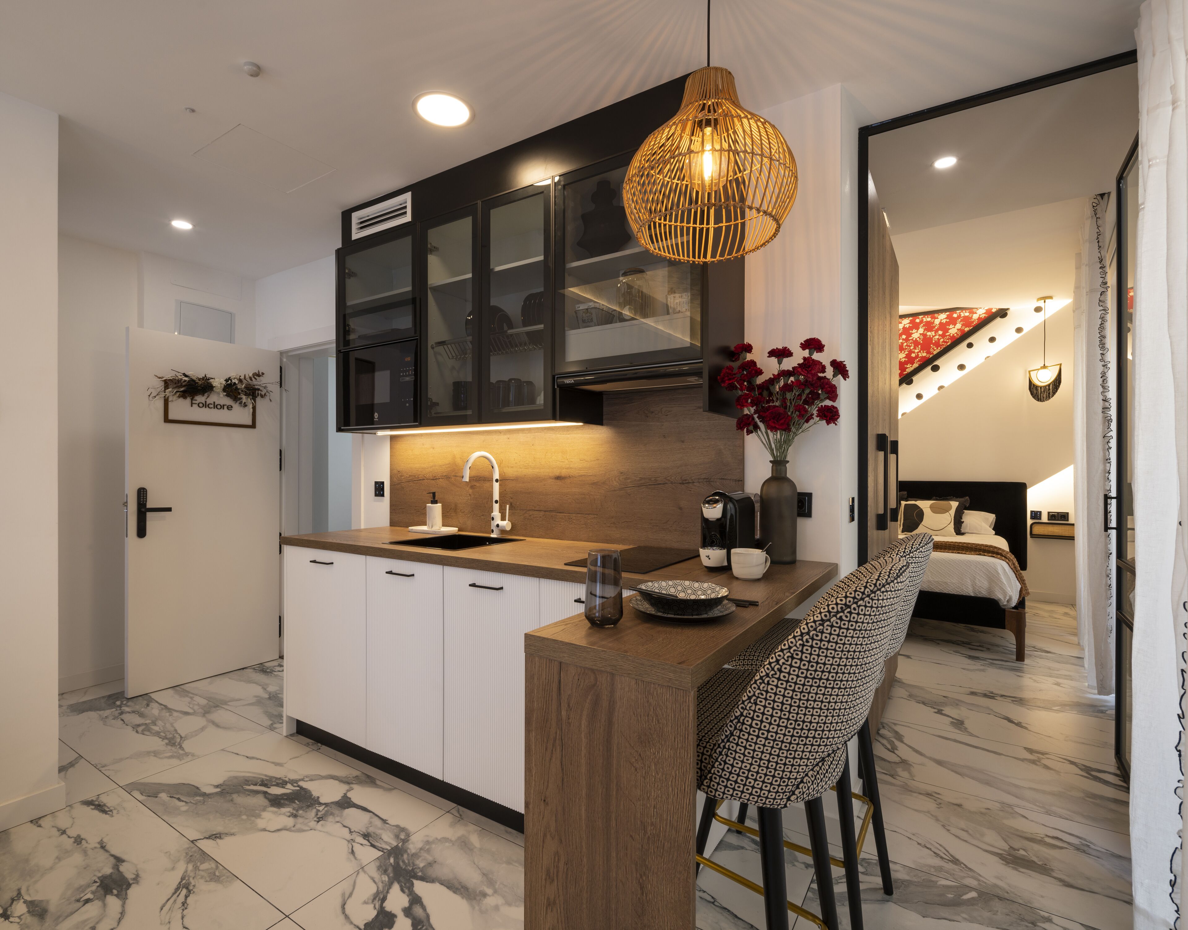 Una cocina moderna con una isla de madera, armarios negros y una lámpara colgante.