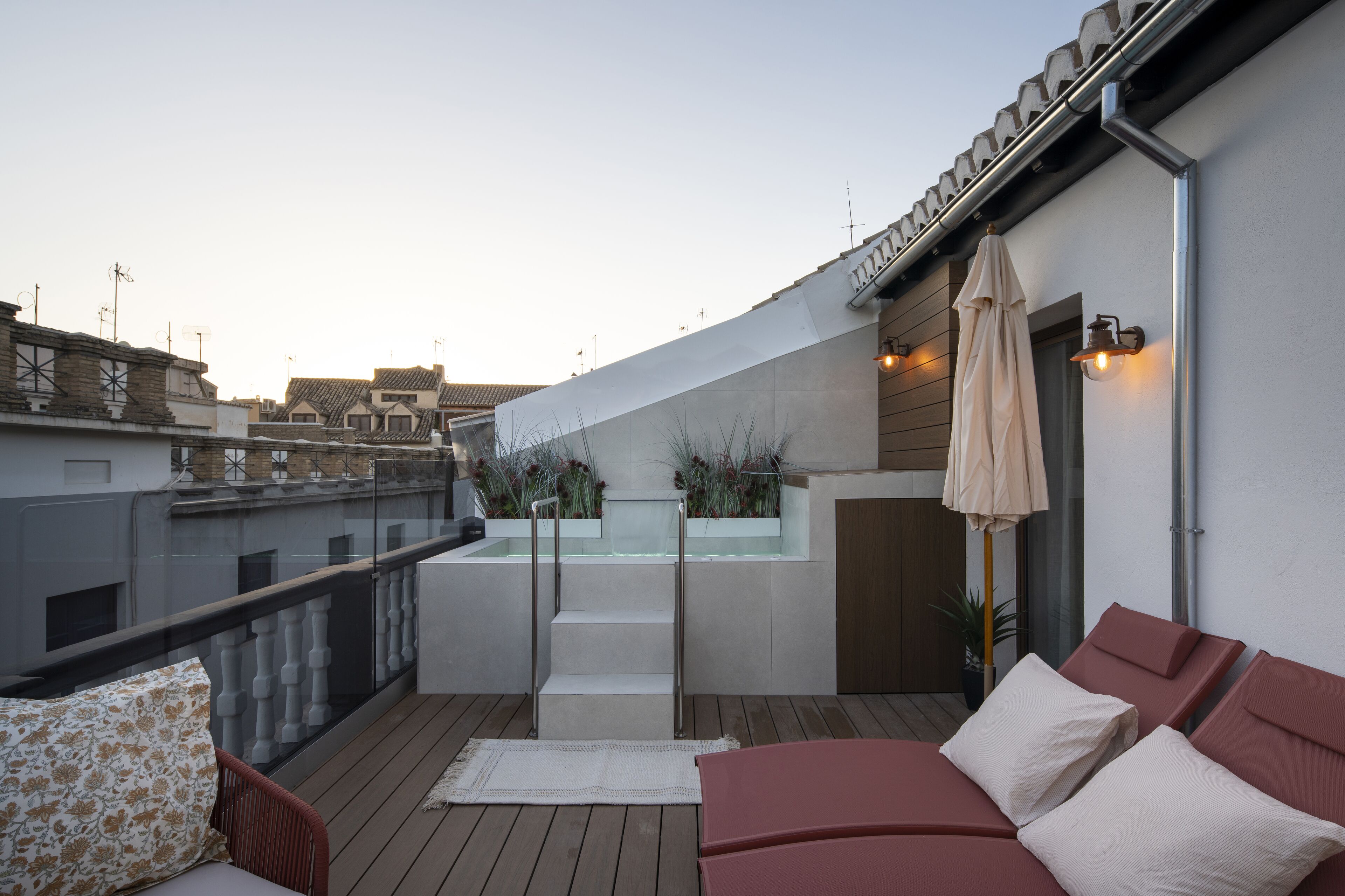 Una terraza en la azotea con piscina, sillas de descanso y una pérgola.