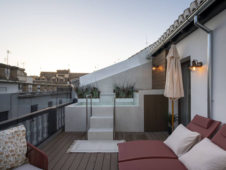 Una terraza en la azotea con piscina, sillas de descanso y una pérgola.