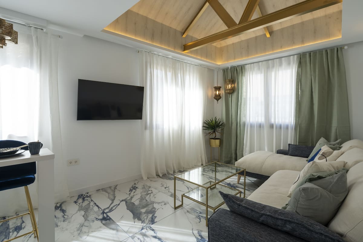 A modern living room with a marble floor, a sofa, a coffee table, and a TV mounted on the wall.