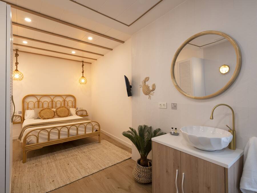 A bedroom with a bed, bedside lamp, and a wall-mounted TV.