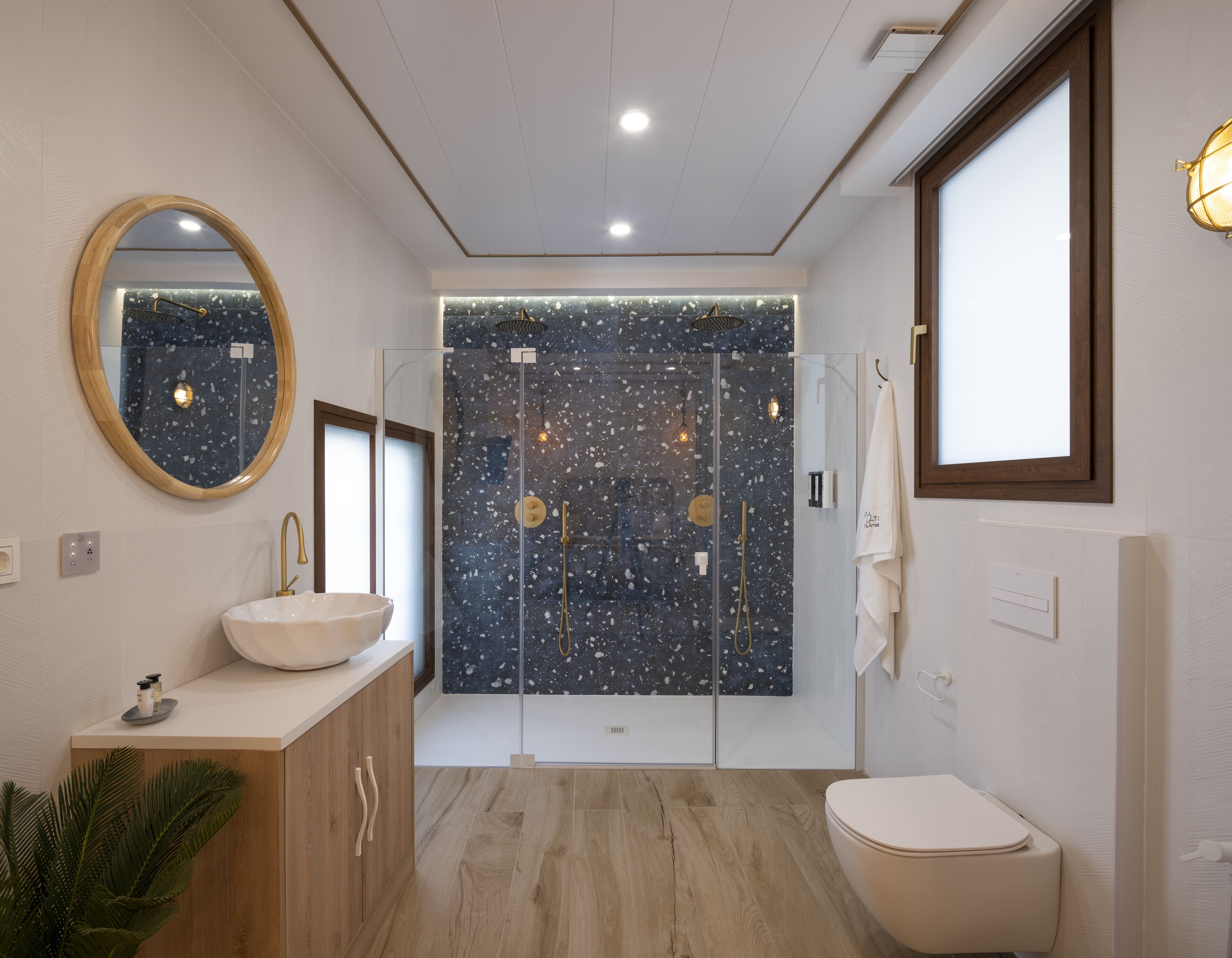 Une salle de bain moderne avec une baignoire sur pieds, un miroir rond et des toilettes.