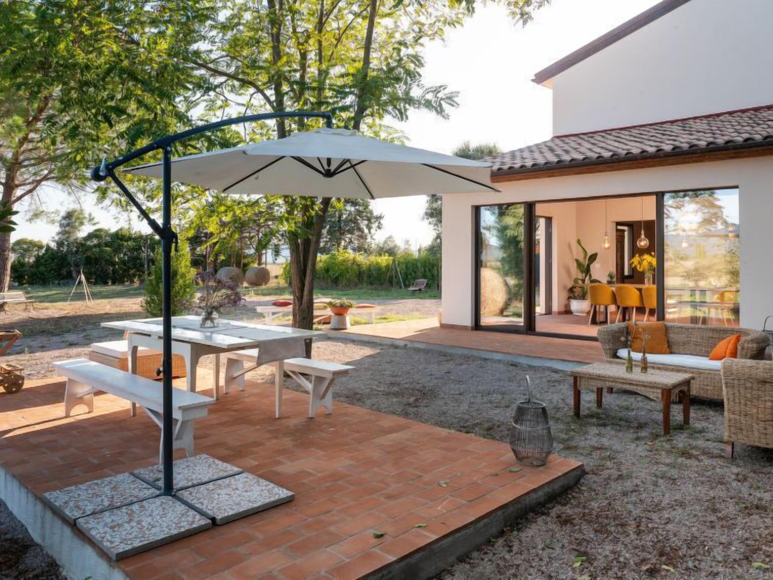 An outdoor patio with a dining table and chairs, a large umbrella, and a wicker sofa.
