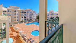 Un hotel a più piani con balconi, una piscina e aree salotto all'aperto.