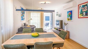 Una sala de estar moderna con una mesa de comedor, sillas, un sofá y un televisor.