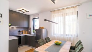 Una cocina moderna con armarios oscuros, una isla central y una zona de comedor con mesa y sillas.
