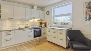Una cocina moderna con armarios blancos, horno empotrado y ventana que proporciona luz natural.